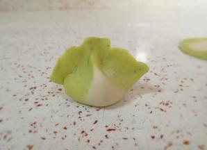 把饺子边缘捏上，然后用两个手的食指和大拇指一起挤捏一下，一个白菜饺子就包好了，有没有很像白菜呢？