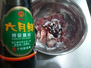 把切好的牛肉片放入大碗内，加入味达美臻品蚝油1勺、六月鲜特级酱油2勺、淀粉1勺。
