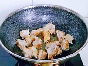 待冰糖成褐色时加入焯水的排骨，炒糖色。