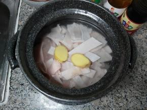 准备一个砂锅，装入猪皮、清水，再把姜块一并放进去，倒入两勺味达美臻品料酒，大火煮至沸腾。