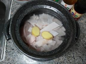 准备一个砂锅，装入猪皮、清水，再把姜块一并放进去，倒入两勺味达美臻品料酒，大火煮至沸腾。
