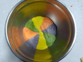 每个颜色的面团分成2份，颜色交错放入容器中，压平