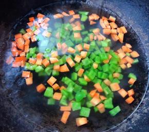 锅中烧开水放入切好的青椒粒和胡萝卜粒焯水时间不要过长刚刚变色漂浮起来即可