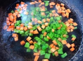锅中烧开水放入切好的青椒粒和胡萝卜粒焯水时间不要过长刚刚变色漂浮起来即可