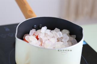 准备好一个干净无油的不粘锅，倒入草莓粒和冰糖，中小火开煮。