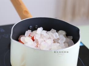 准备好一个干净无油的不粘锅，倒入草莓粒和冰糖，中小火开煮。