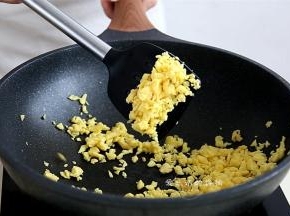 打散的鸡蛋放入锅里，小火慢煎，并用锅铲将鸡蛋铲碎，捞出备用