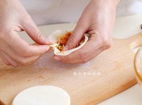 取一个饺子皮，稍微擀大一圈，包入适量的馅料，按照包包子的首发捏好褶子包起来。