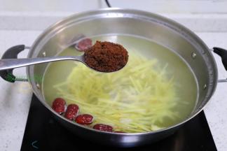 这个时候的锅里水飘出一个浓香的姜味，加入2-3勺纯红糖，并且用勺子搅拌，继续小火1分钟。