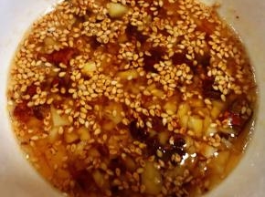 锅中倒入适量油加热放入花椒炸香取出花椒将油趁热直接倒入蒜粒碗中瞬间满屋飘香
