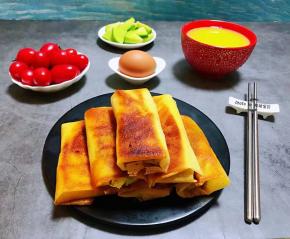 诱人的时蔬春卷装入容器中搭配鸡蛋、小米粥、萝卜小菜，水果就是标配的一餐