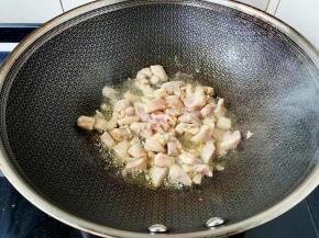 炒出香味放入鸡腿丁大火翻炒。