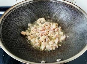 炒出香味放入鸡腿丁大火翻炒。