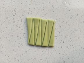 绿色面团擀薄片，切成长方体，切成如图的长三角状做叶子，叶子的长度根据玫瑰花的高度来切