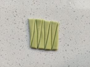绿色面团擀薄片，切成长方体，切成如图的长三角状做叶子，叶子的长度根据玫瑰花的高度来切
