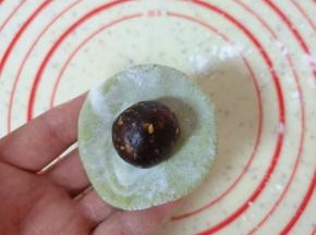 将一个小糯米面团用手压扁，放上枣泥果仁馅。