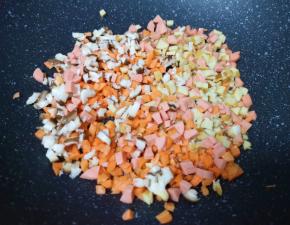 不粘锅内倒少许食用油烧热，下入香菇、胡萝卜、豆腐干和火腿肠。