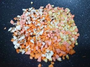 不粘锅内倒少许食用油烧热，下入香菇、胡萝卜、豆腐干和火腿肠。