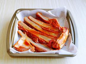 取出腌制好的羊排，放在垫有油纸的烤盘中。