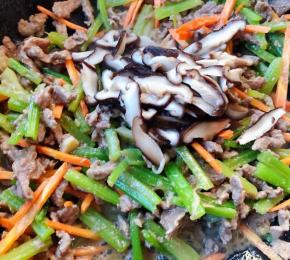 放入胡萝卜和香菇片快速翻炒均匀