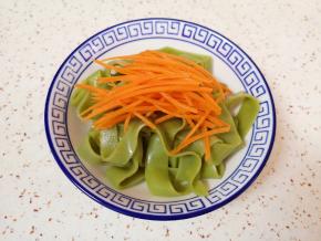 切好的凉皮装入碗里，放上胡萝卜丝。