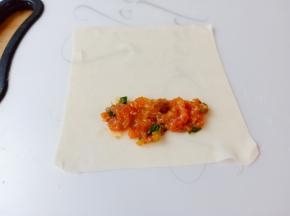 把馄饨皮平铺在板上，放上馄饨皮，肉馅放在上面。