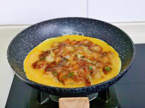 煎好的扇贝肉翻面煎1分钟，将蛋液沿着扇贝煎周围缓缓倒入，小火煎制蛋液表面凝固。