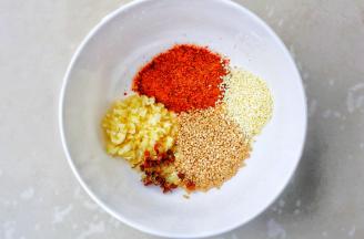 准备调料碗，碗中加蒜末，辣椒面，白芝麻，五香粉，花椒粒。