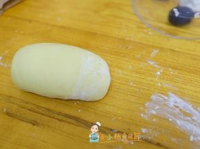 面包机里面取出黄色的南瓜面团，手揉一下至表面光滑