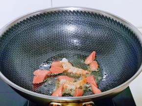 起油锅，加入火腿肠与黑虎虾煸炒至变色。