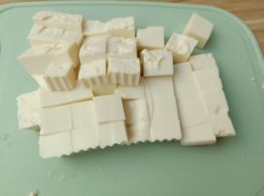 豆腐对半切开，再切成小块。