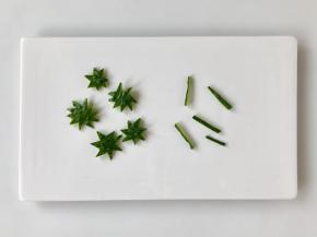 黄瓜用刀削下大片皮，用小刀刻出草莓蒂和梗。