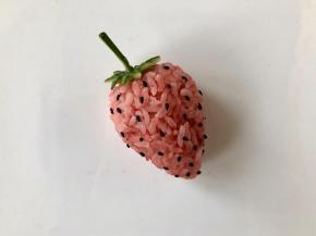 在草莓饭团表面粘上熟黑芝麻，这一步可以让小朋友来完成哦！这一步需要耐心哦～