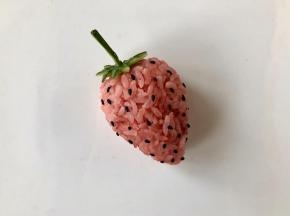 在草莓饭团表面粘上熟黑芝麻，这一步可以让小朋友来完成哦！这一步需要耐心哦～