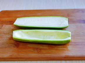 首先将西葫芦洗干净，从中间切开，再借助小勺把瓜瓤挖干净。