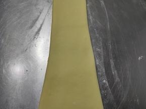 取一个擀卷的面团，将其用手掌轻轻压扁，再次用擀面杖轻轻的擀长。