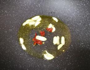 炒锅内倒适量的食用油烧热，下入蒜片和干红辣椒炒香。