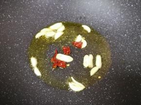 炒锅内倒适量的食用油烧热，下入蒜片和干红辣椒炒香。