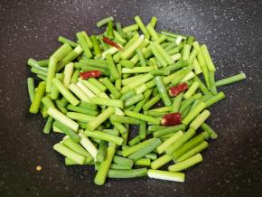 锅底留余油，下入蒜苔和干红辣椒，翻炒至变色。