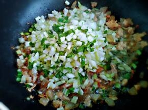 出香后下入青菜梗，调入糖、味精提鲜。翻炒几下把把菜倒入电饭煲中，按煮饭建开始煮饭。
