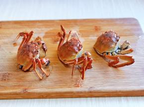 取出煮好的蟹，放在砧板上，把下面的壳掰掉。