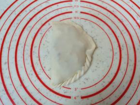 捏花边，先提起一角向内折，然后继续拉起卷过去（如图）。