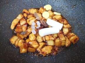 加入料酒，翻炒至料酒挥发掉一半，加入冰糖、葱姜香料炒香。