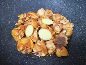 下入鸡块大火爆炒，将鸡肉的水分炒出来，让鸡皮上色，放姜片和料酒翻炒均匀。