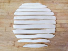 揉好的面团擀成一个大饼状，切成宽厚一致的长条形。