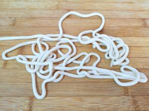 将饧好的面条从盆里取一根出来，先把面头部分搓细一点，然后用左手拿着面条，右手一边拉一边甩出来（如图）。