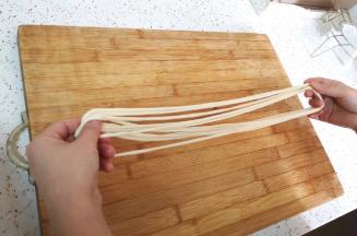 拉好的面条像缠毛线一样绕在手上，在案板上摔几下，拉条子就做好了。