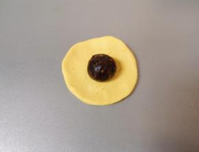 取一个搓好的南瓜糯米球压扁，放上枣泥果仁馅。