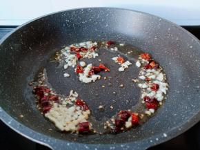 锅里冷油下蒜末与干辣椒段炒香。