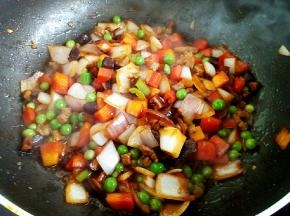 变色后放入生姜、八角，各种蔬菜丁翻炒。烹入料酒、生抽、老抽，盐，糖，炒出香味。